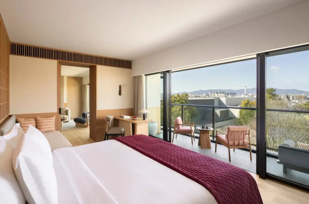 Helles Schlafzimmer einer Suite mit Balkonblick auf die Skyline von Kyoto