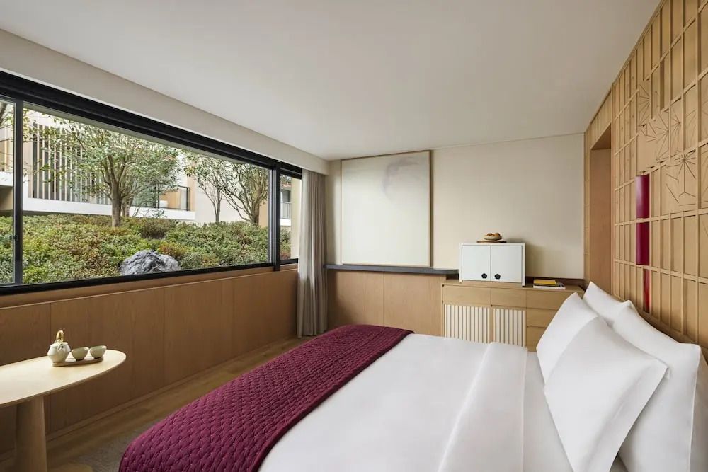 Modernes Superior Doppelzimmer mit großen Fenstern und Blick auf den Garten