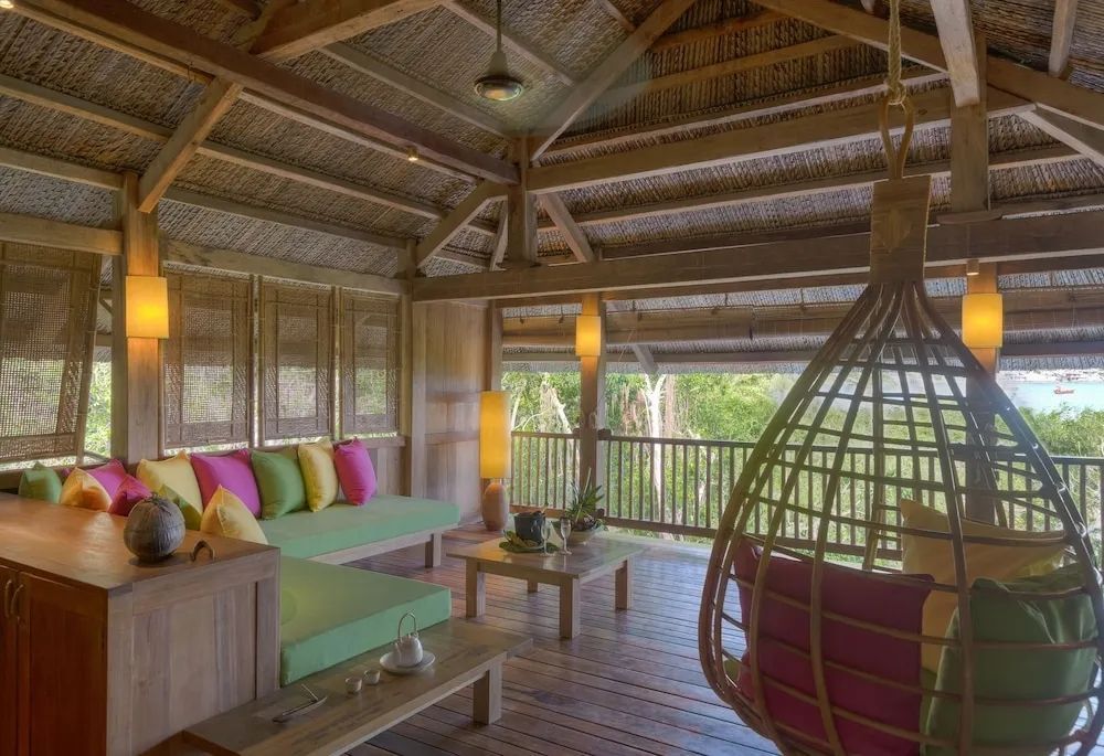Gemütlicher Wohnbereich mit hängendem Sessel und Holzmöbeln im Six Senses Ninh Van Bay
