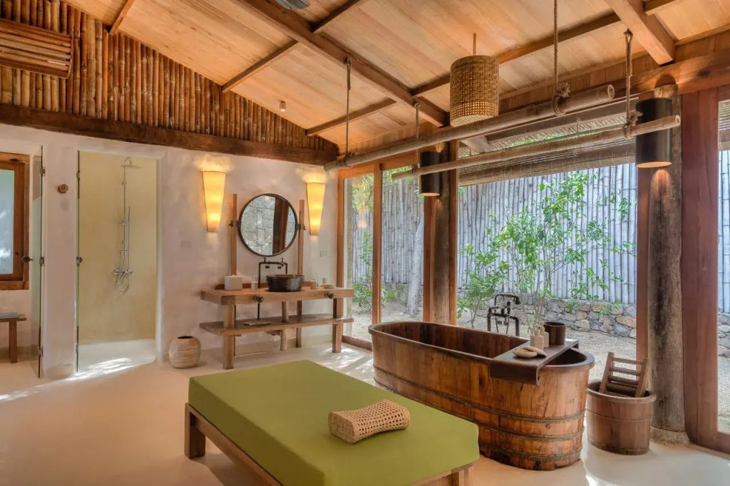Badezimmer mit freistehender Holzwanne und luxuriösem Ambiente im Six Senses Ninh Van Bay
