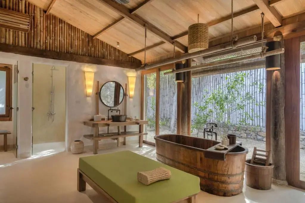 Luxuriöses Badezimmer mit freistehender Holzbadewanne und grüner Liege
