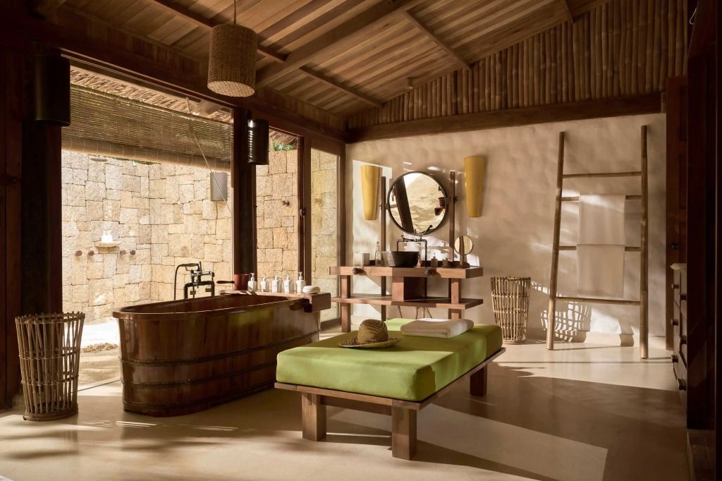 Elegantes Badezimmer mit Holzbadewanne, großem Spiegel und grüner Liege