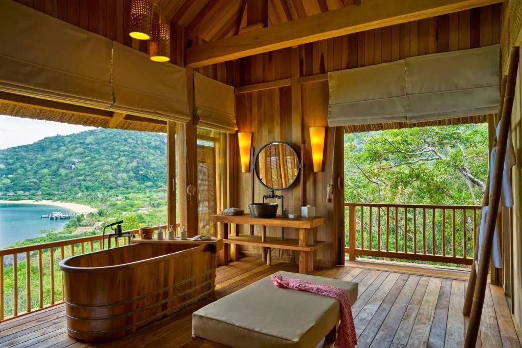 Holzbadezimmer mit freistehender Badewanne und Blick auf die grüne Umgebung.