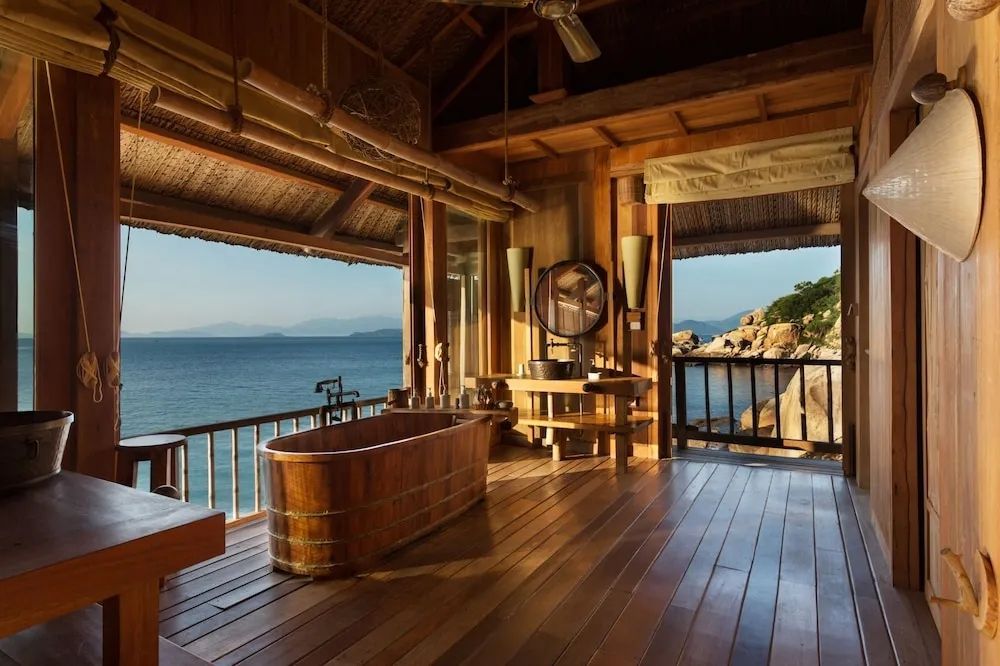 Holzbadewanne in offenem Raum mit Meerblick und Felskulisse