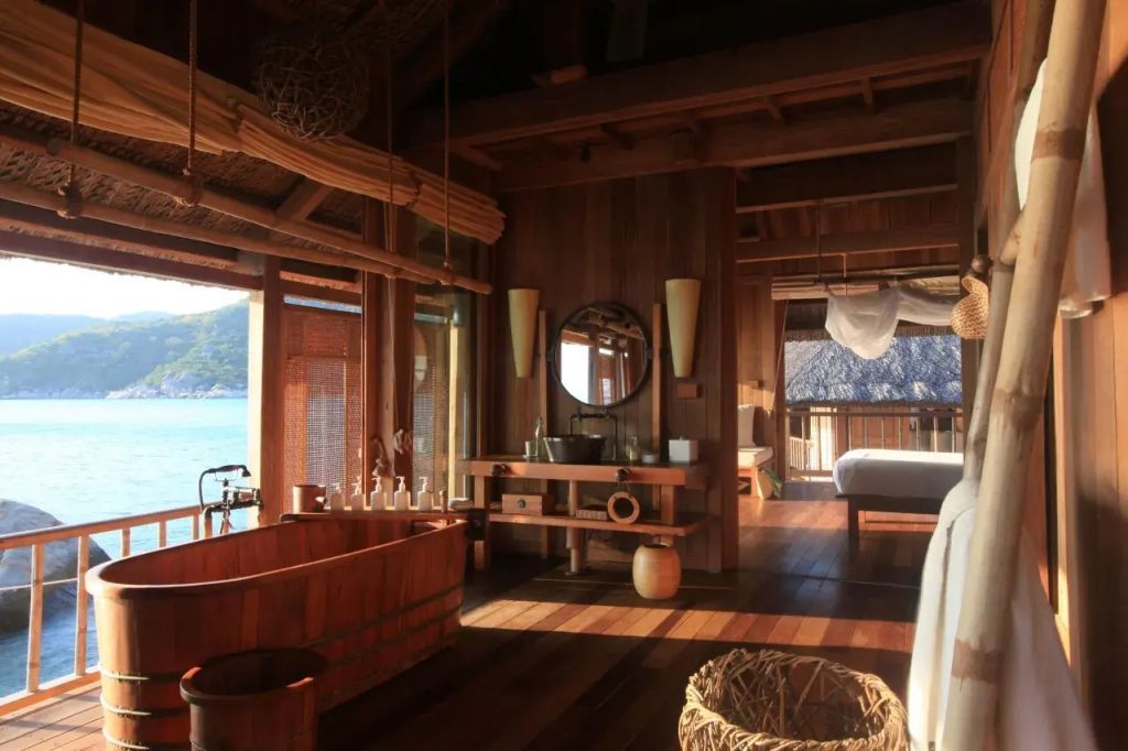 Elegantes Badezimmer mit Holzbadewanne und Blick auf das Meer im Six Senses Ninh Van Bay