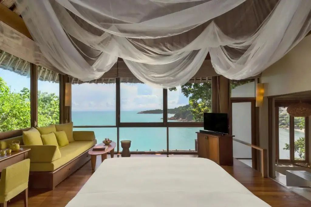 Luxuriöses Schlafzimmer mit Meerblick und Baldachin im Hotelzimmer.