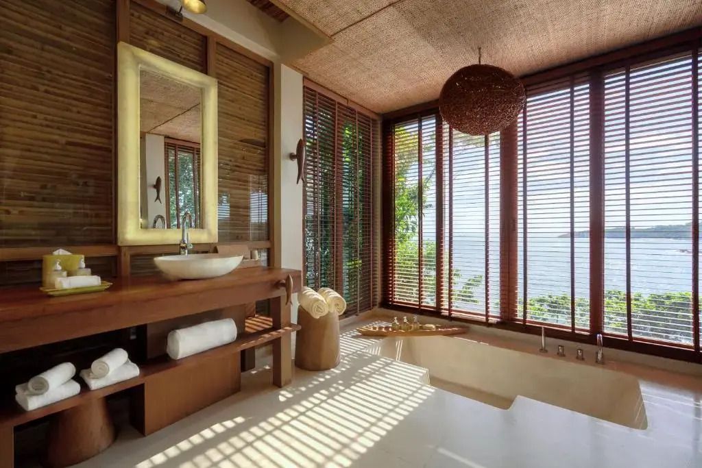 Modernes Badezimmer mit freistehender Badewanne und großem Fenster zum Meer.