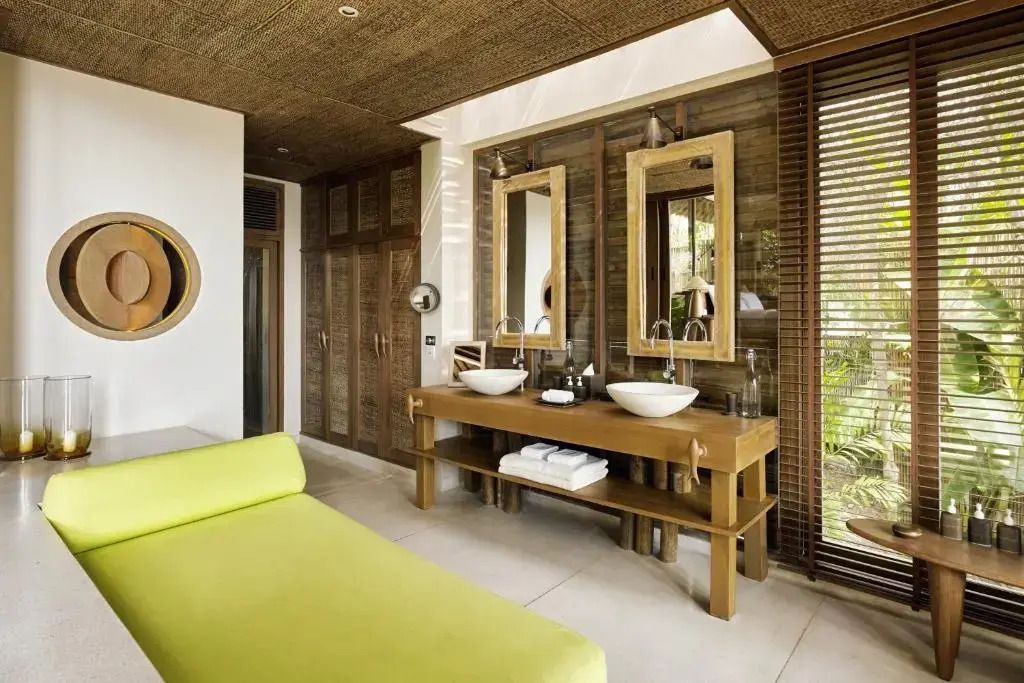 Modernes Badezimmer mit zwei Waschbecken und gemütlicher Sitzgelegenheit in natürlichem Design