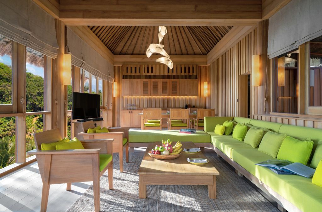 Gemütliches Wohnzimmer mit Holzmöbeln und grünen Akzenten, offen zum Außenbereich