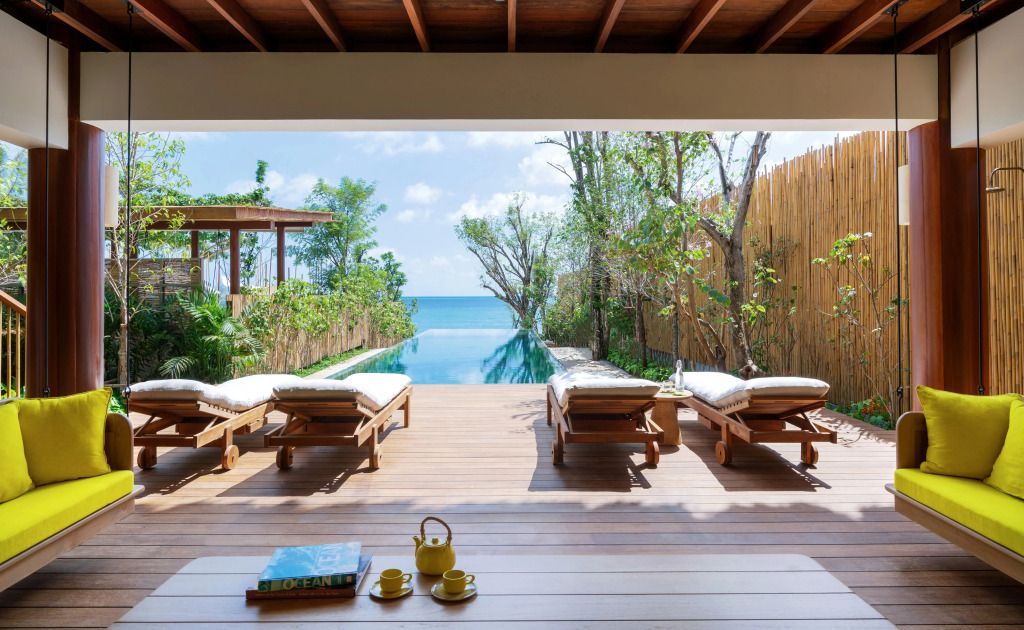 Privater Pool mit Holzterrasse, Liegestühlen und Blick auf das Meer
