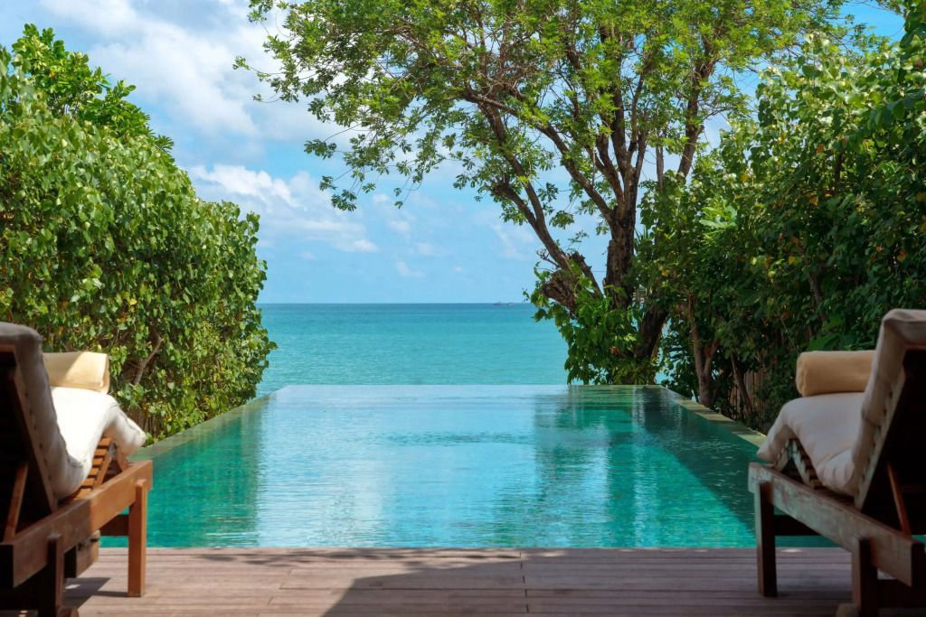 Infinity-Pool mit Blick auf das türkisblaue Meer und üppigem Grün