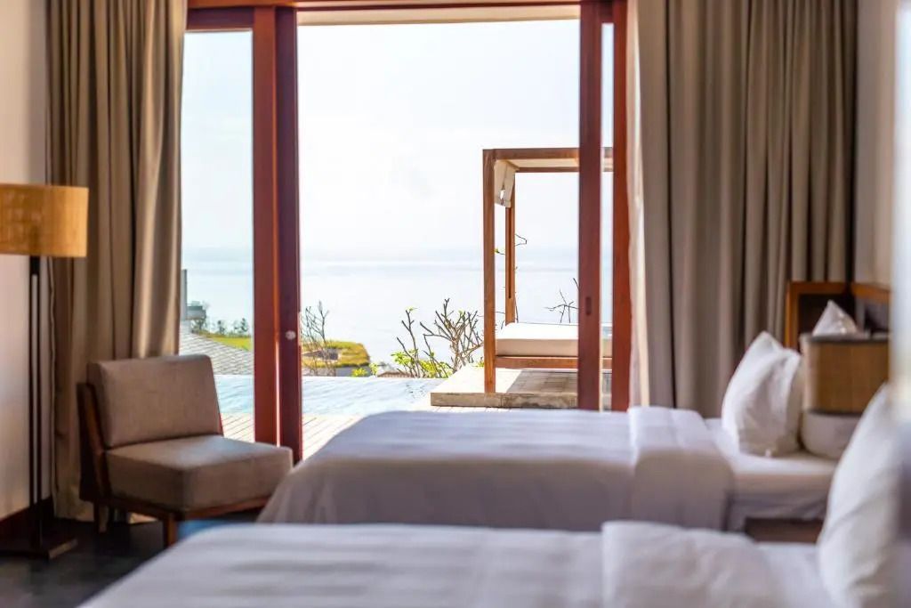 Zimmer mit zwei Betten, Balkontüren mit Meerblick und privater Terrasse.