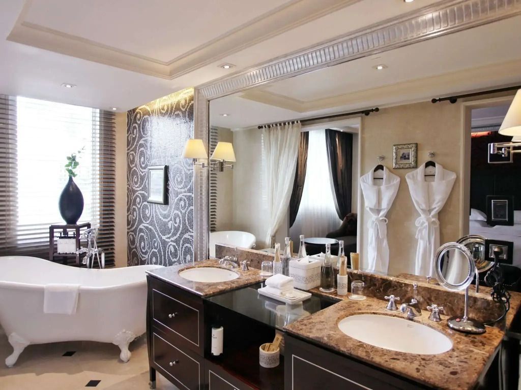 Luxuriöses Badezimmer mit Doppelwaschbecken und freistehender Badewanne im Sofitel Legend Metropole Hanoi.