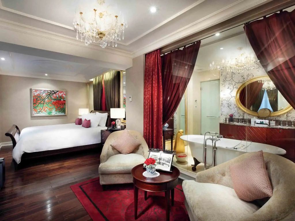 Geräumige Suite mit Doppelbett, roten Vorhängen und eleganter Einrichtung.