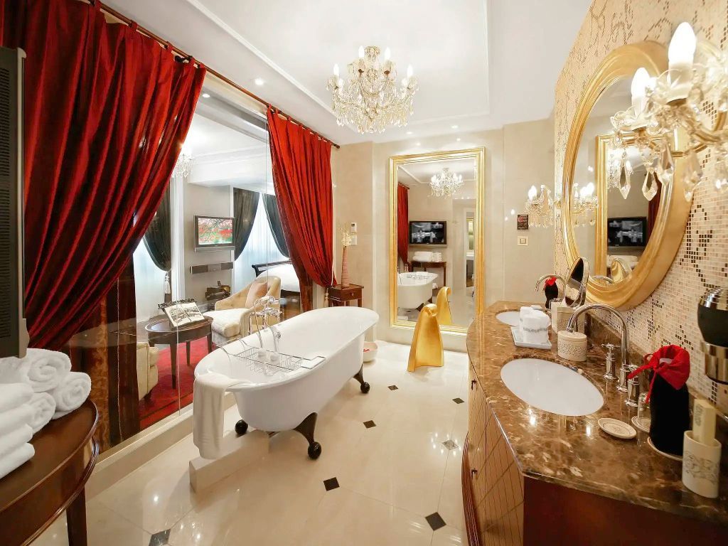 Luxuriöses Badezimmer mit Marmor, freistehender Badewanne und goldenen Akzenten.
