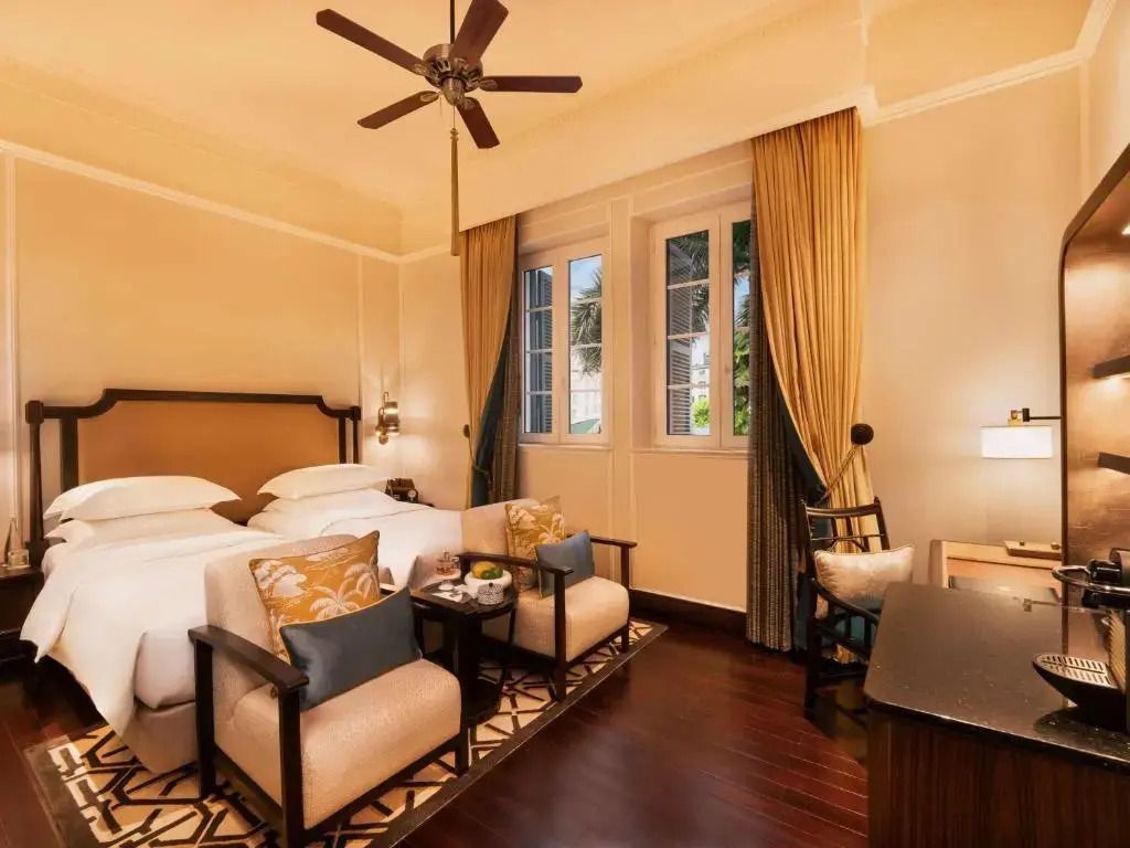 Luxuriöses Doppelzimmer mit Doppelbett und eleganten Sesseln im Sofitel Legend Metropole Hanoi