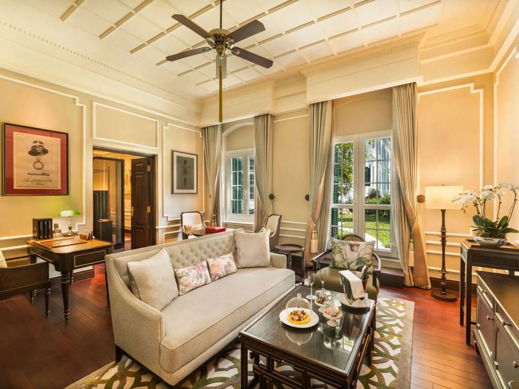 Heller Wohnbereich mit Sofa und großen Fenstern in der Somerset Maugham Suite.