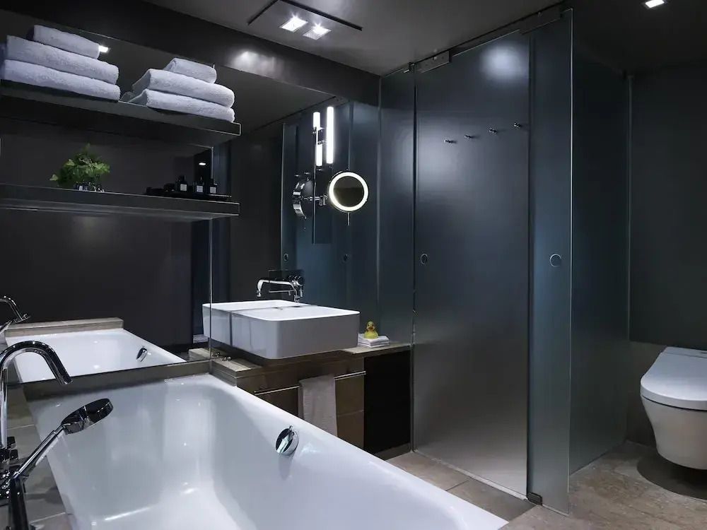 Modernes Badezimmer mit Badewanne und Regendusche im Sofitel Munich Bayerpost