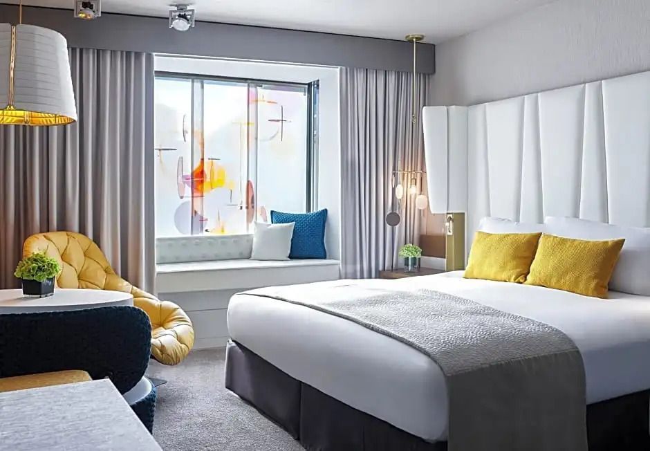 Luxus Doppelzimmer mit großem Bett, farbigen Kissen und Sitzbereich am Fenster