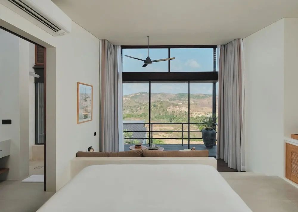 Schlafzimmer mit Fensterfront und Aussicht auf die Natur