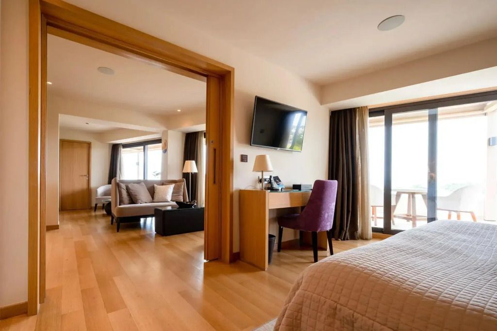 Elegante Suite mit Holzboden, großem Bett, Schreibtisch und Balkon mit Ausblick.