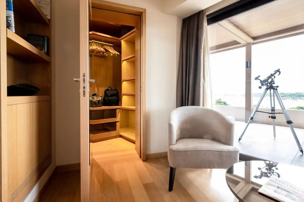 Offener Kleiderschrank mit Stuhl und großem Fenster im Hintergrund.