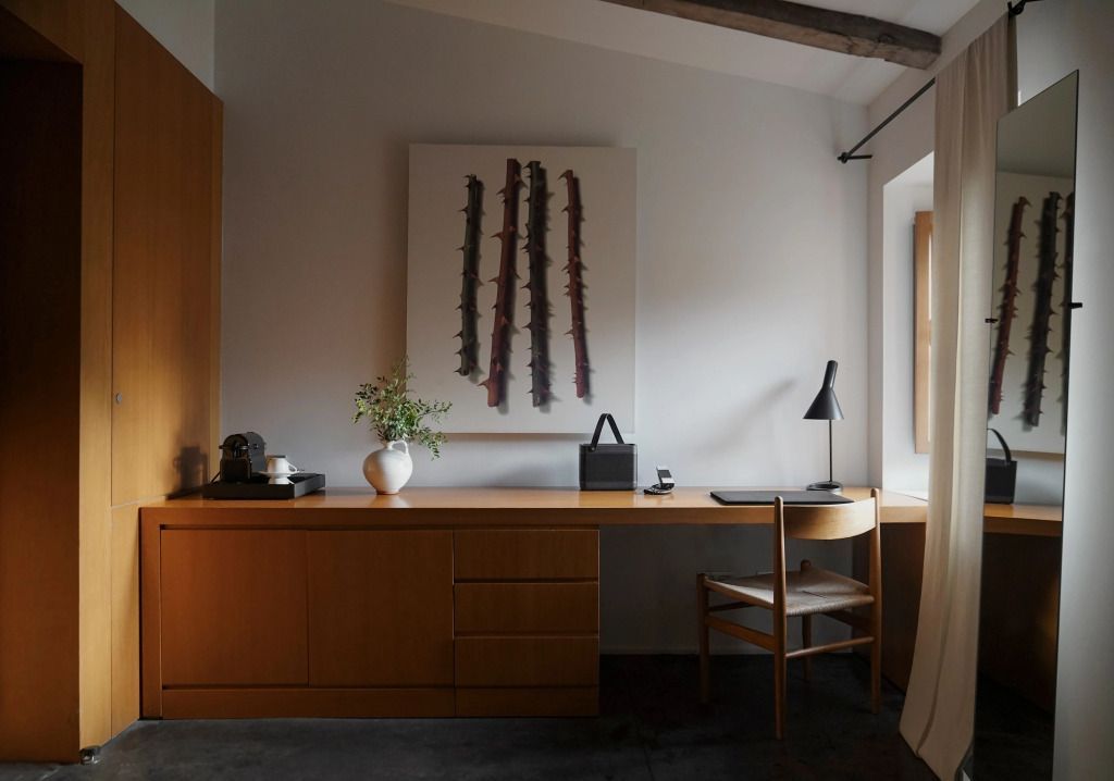 Holzschreibtisch mit Kunst und dezenter Beleuchtung im Deluxe Zimmer.