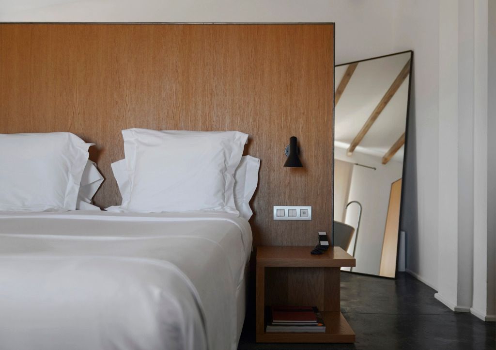 Komfortables Bett mit minimalistischer Einrichtung und großem Spiegel in Junior-Suite