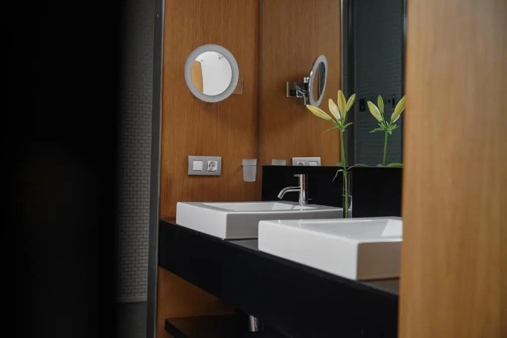 Moderne Badezimmerarmaturen mit Holzverkleidung und weißen Waschbecken