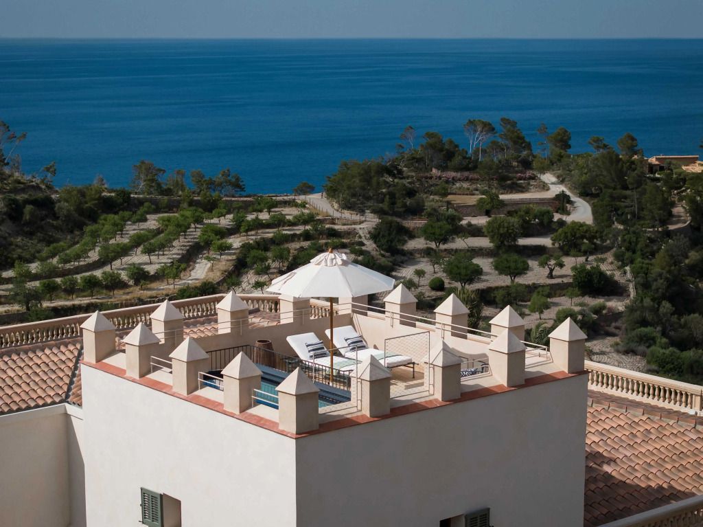 Terrasse mit Liegestühlen und Sonnenschirm mit Blick auf das Meer