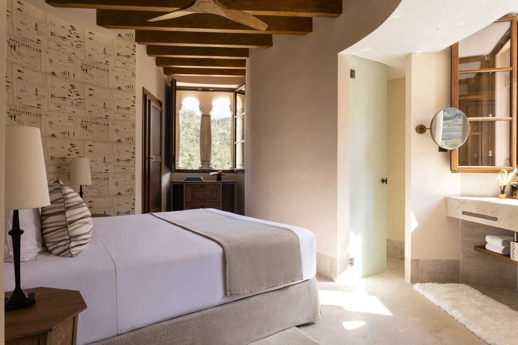 Schlafzimmer in der Suite mit Holzbalkendecke und offenem Fenster mit Blick ins Grüne.