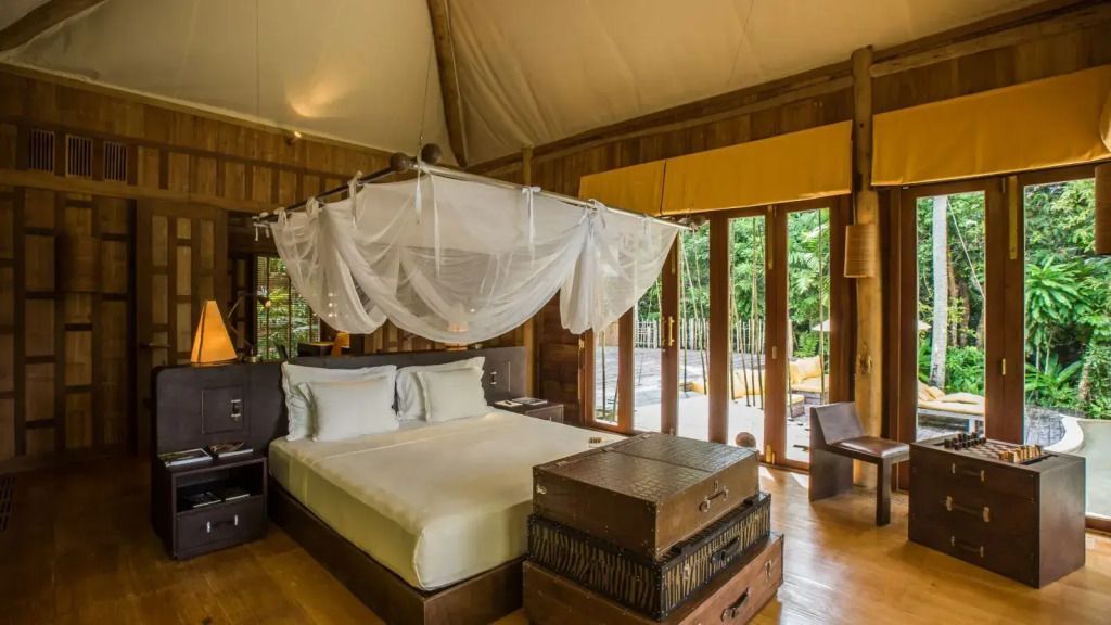 Helles Zimmer mit Himmelbett und Panoramafenstern zur Terrasse.