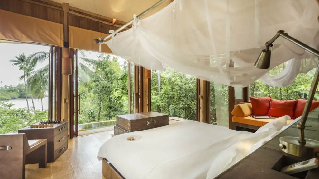 Schlafzimmer mit Himmelbett, offenen Türen zum Garten und hellem Interieur.