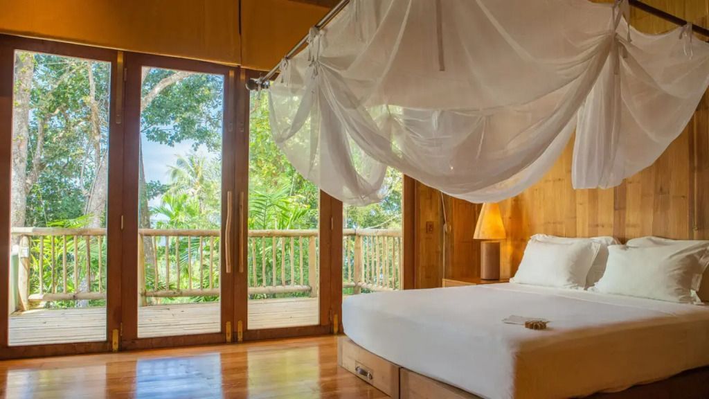 Schlafzimmer mit Holzinterieur und großem Fenster mit Blick ins Grüne