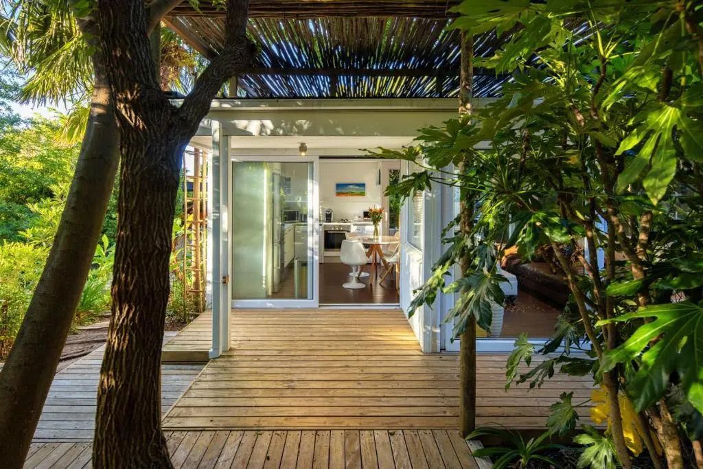 Bungalow-Terrasse mit Holzboden und üppiger Gartengestaltung