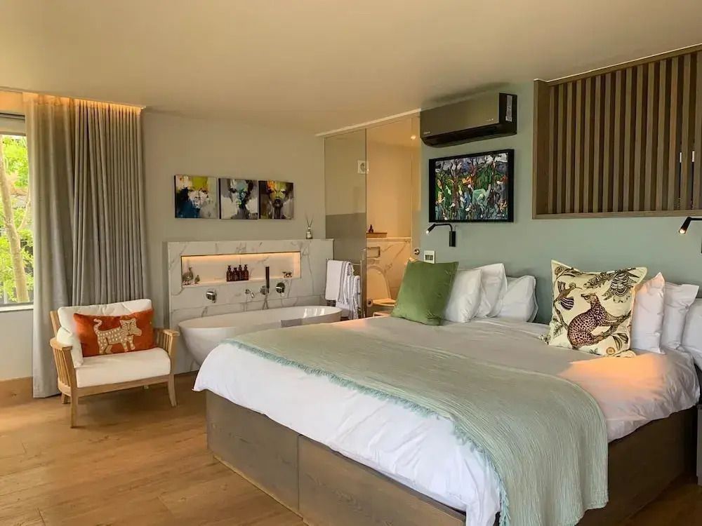 Familienschlafzimmer mit Kingsize-Bett, modernen Kunstwerken und freistehender Badewanne.