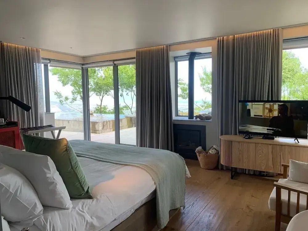 Zimmer mit großen Fenstern, Blick auf die Terrasse, Kingsize-Bett und Flachbildfernseher.