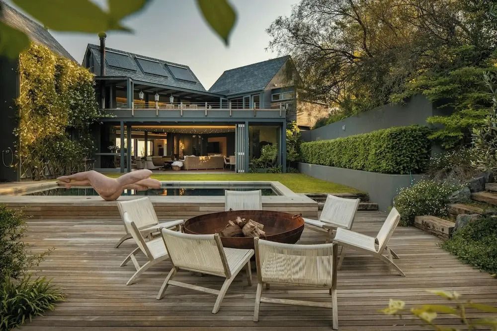 Gartenbereich mit Sitzgelegenheiten und Feuerstelle vor moderner Villa