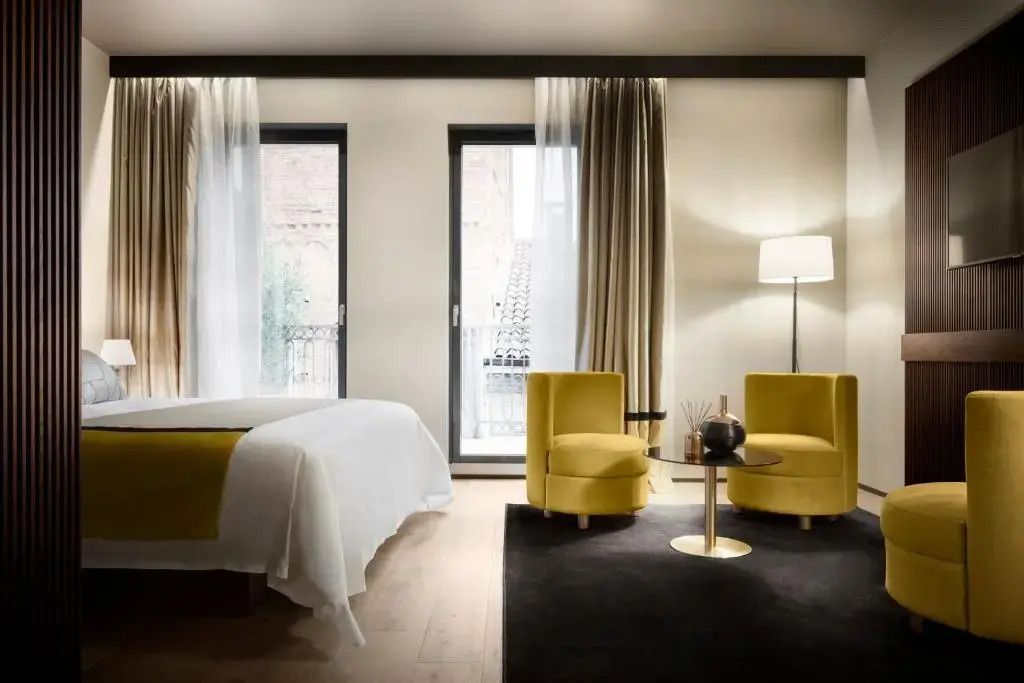 Helles Zimmer mit Doppelbett, gelben Sesseln und großen Fenstern in elegantem Stil