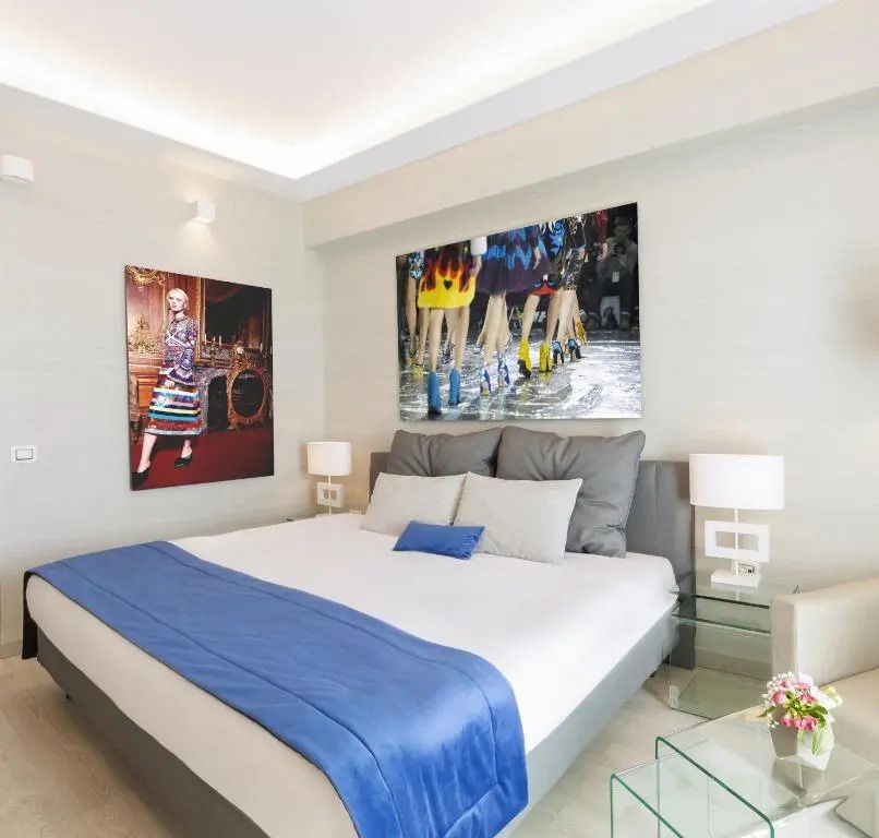 Modernes Doppelbettzimmer mit Kunstwerken an den Wänden und blauen Akzenten.