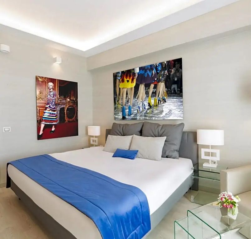Modernes Zimmer mit Kunstwerken und blauen Bettakzenten, stilvoll eingerichtet.