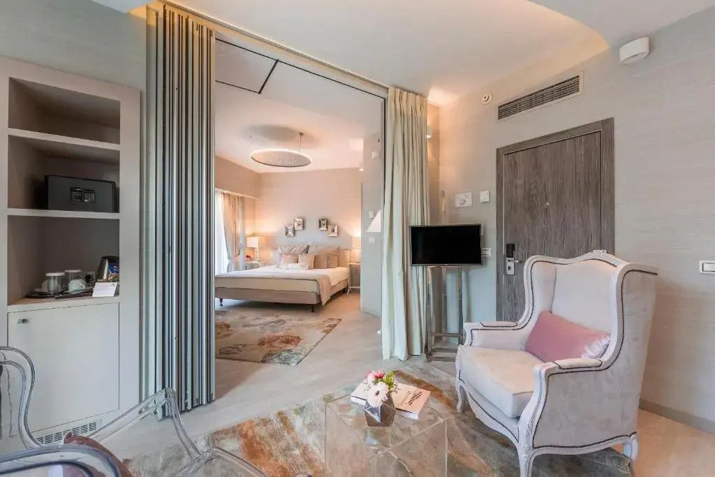 Elegant eingerichtetes Zimmer mit Sessel und Fernseher sowie großem Bett