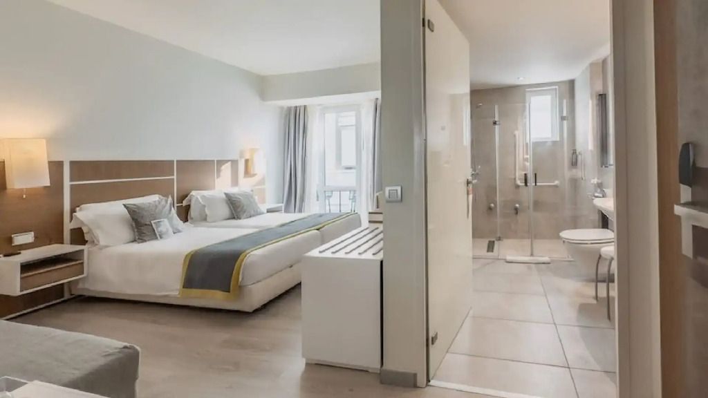 Modernes Hotelzimmer mit Doppelbett, helle Einrichtung und Fenster im Bad