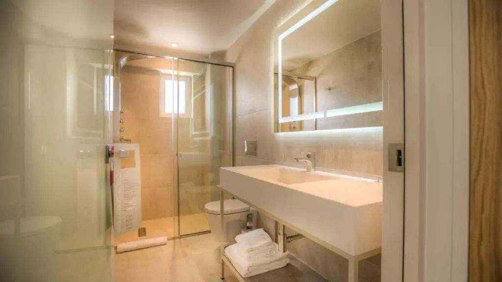 Modernes Badezimmer mit Glasdusche und beleuchtetem Spiegel