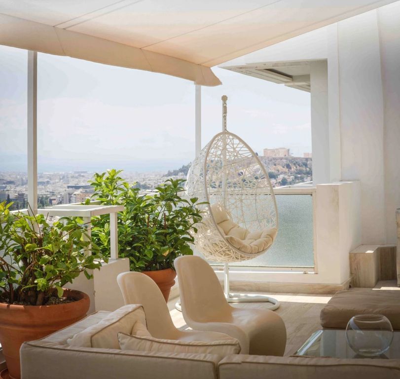 Suite-Balkon mit Hängesessel und atemberaubendem Blick auf die Stadt.