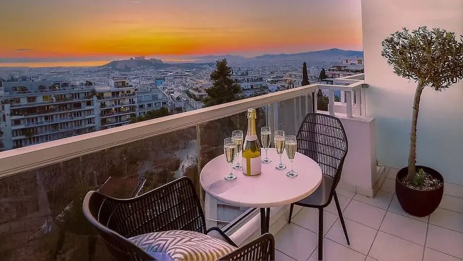 Balkon mit Sitzbereich und Champagner mit Blick auf den Sonnenuntergang über der Stadt