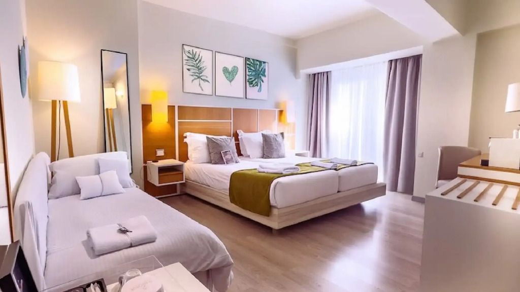 Helles Signature Zimmer mit Doppelbett, modernen Möbeln und Balkonblick.