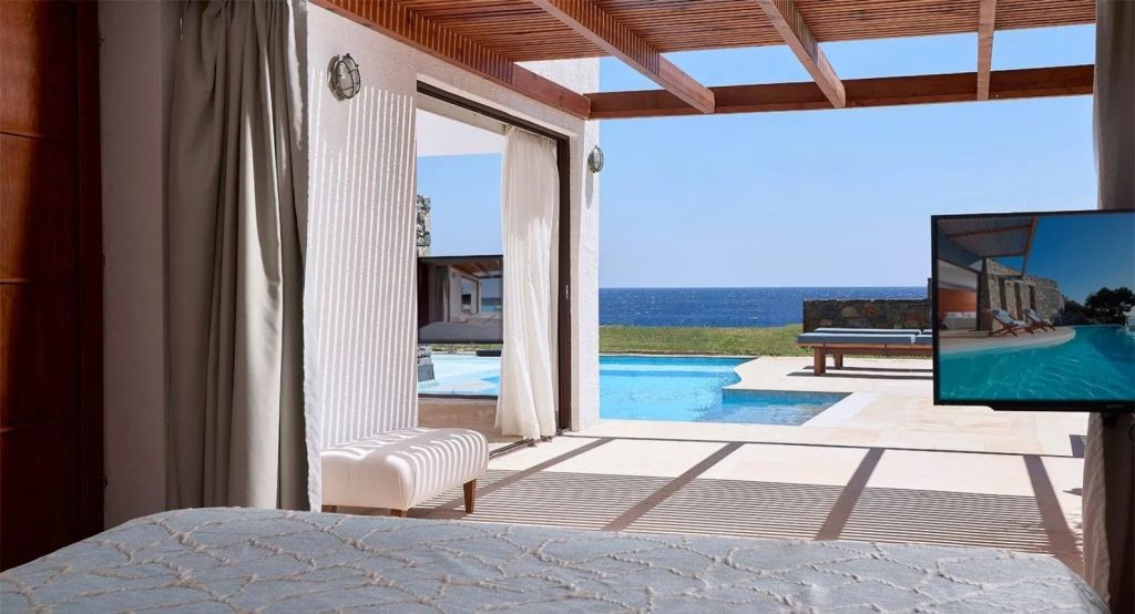 Helle Suite mit Blick auf Pool und Meer. Moderne Einrichtung mit offenem Zugang zur Terrasse.