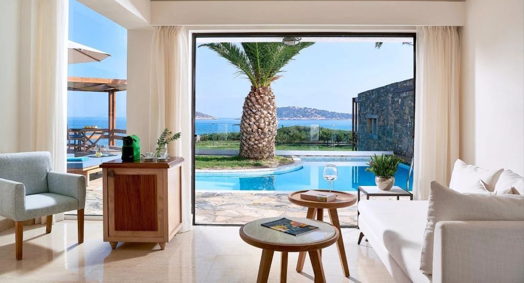 Elegantes Zimmer mit Blick auf Pool und Meer durch große Fensterfront