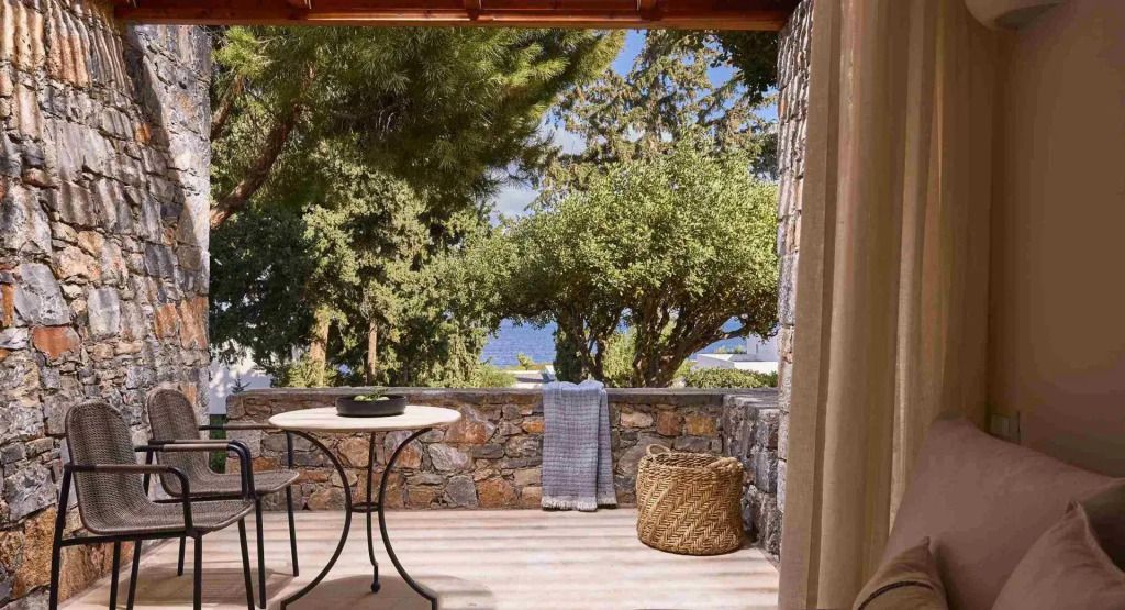 Terrasse mit Sitzgelegenheit und Blick auf Bäume und Meer
